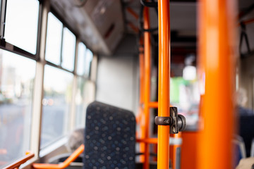 Orange metallic bars in a bus with seats in background – Interior of a comfortable and practical public transport in the middle of the day