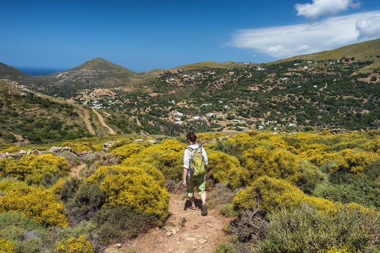 Woman with a backpack hiking on a hiking trail on Andros island, Greece