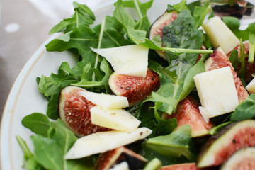 Fresh fig and pecorino chunks on a bed of green rocket leaves