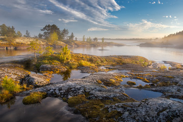 Stunning view of the rocks covered with yellow moss and sun-drenched islands. Beauty of summer nature concept background. Foggy and sunny landscape. Ladoga lake.Archipelago.National Park of Karelia. 