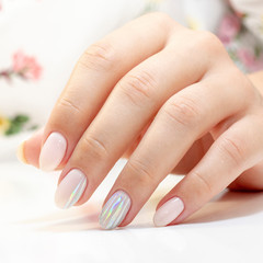 manicure. the manicurist made a manicure and gel polish on the clients nails in gentle tones with stripes of foil gloss