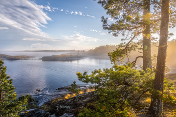Foggy landscape of northern nature. Magnetic sunny view of the islands and fjords. Awesome sunrise on the lake. Ladoga lake. Smoky summer landscape. Primeval Russia. Archipelago. Republic Karelia.