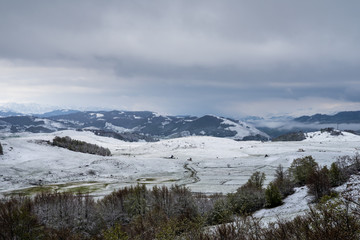 Fototapeta premium Montenegro, Perfect scenery of forest land covered by white snow in spring season from above in hilly nature landscape of durmitor national park near zabljak