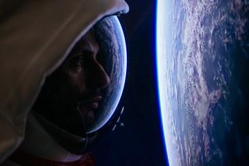 Astronaut looking deep space, galaxy and planets from the window of his capsule. Concept about...