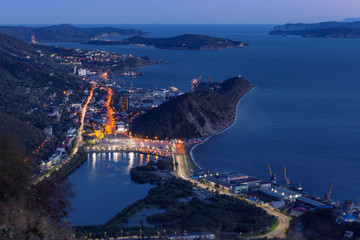 night city on the coast of the ocean with a bright illuminated road. Night top view of the city and the Pacific Ocean.Volcano City. Kamchatka. Petropavlovsk-Kamchatka region. 