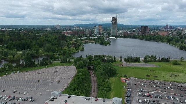 Drone footage high above Ottawa facing the train tracks through Carelton University with a train going by and the Queens Guards Training on  fields near Dows Lake and the O-Train.