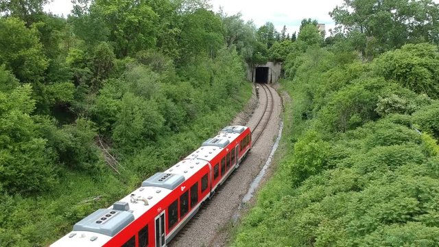 Dynamic drone footage over the O-Train going towards a tunnel in Ottawa, Ontario, Canada.