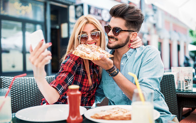 Loving couple sitting in the cafe and eating pizza. Consumerism, food, lifestyle concept
