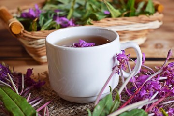 Obraz na płótnie Canvas Traditional Russian herbal drink. Ivan-tea in a Cup close-up on a wooden table. It has a positive effect on the human body.