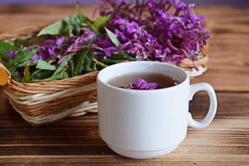 Traditional Russian herbal drink. Ivan-tea in a Cup close-up on a wooden table. It has a positive...