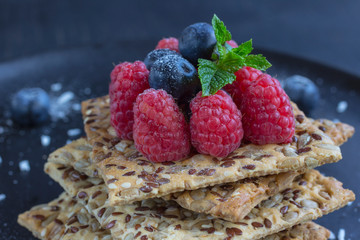Cookies with whole grains. Raspberry and blueberry berries on top. black background.