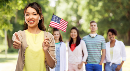 citizenship, ethnicity and independence day concept - happy asian young woman with american flag over international group of friends in summer park background