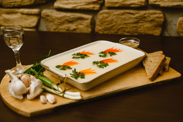Fototapeta na wymiar aspic, decorated with carrots, parsley on a wooden background. Russian-national food with moonshine, vodka, garlic, green onions and bread