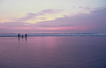 Young family with child on the beach at sunset time