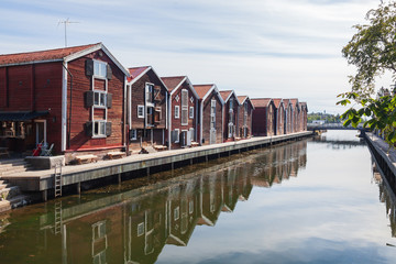 Old red wooden port warehouses next to the water in Hudiskvall historic center, Sweden