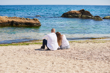 Couple in love hugging on a tropical beach with a turquoise water and rocks in the background