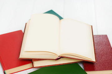 stack of books lies on a white wooden table, one book is covered, there is a place for text.