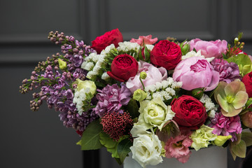 Bouquet of different beauty flowers in round present box on dark background