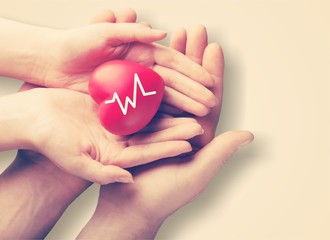 Man and woman holding red heart in hands on blurred background