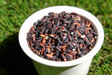 Rice in a container placed on a green background.