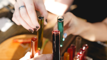 Test tubes with multi-colored liquid. Alcohol in test tubes dark bar. Photo from the bar in Lviv Ukraine. Hands clink glasses