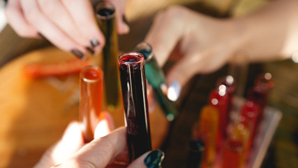 Test tubes with multi-colored liquid. Alcohol in test tubes dark bar. Photo from the bar in Lviv Ukraine. Hands clink glasses