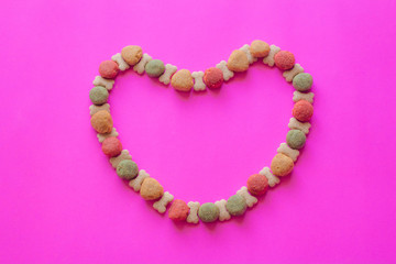 Creative valentines concept photo of Dog food and a heart be lovely on pink background.