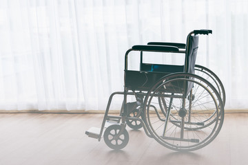 Fototapeta na wymiar Wheelchair Parked on wooden floors with white curtains background, to health concept.