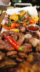 Mixed grilled meat platter. Assorted delicious grilled meat with vegetable. Mixed grilled meat with pepper sauce and vegetables.