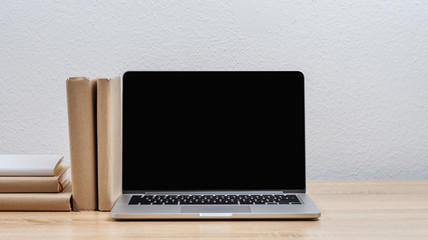 Fototapeta premium Laptop with open screen on the desk with books. Mock up.