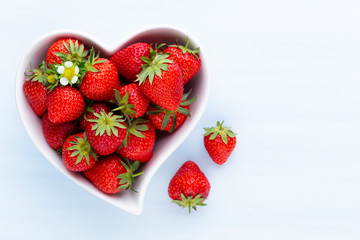 Strawberry heart. Fresh strawberries in plate on white wooden table. Top view, copy space.