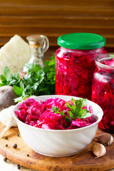 Homemade preserving. Fermented food. Salad Cabbage with Beetroot on the kitchen wooden background.