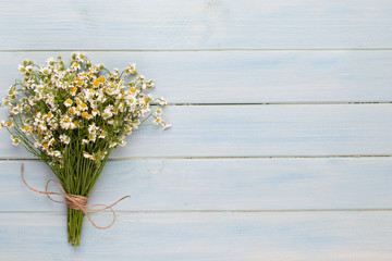 Sea salt, aromatherapy oil in bottles and chamomile on vintage wooden background.
