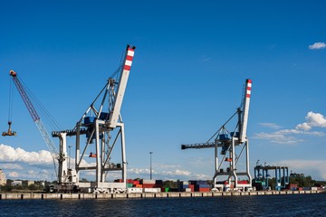 Fototapeta premium Huge crane for loading containers in the cargo terminal of sea port. Summers clear dday. Blue sky. Copy space.
