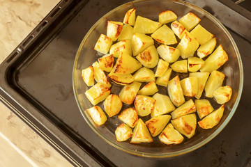 Delicious baked potatoes on glass plate, black background