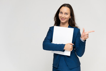Portrait of a young pretty brunette manager woman of 30 years in a business blue suit with beautiful dark hair. Standing with a folder on a white background, talking, showing hands, with emotions