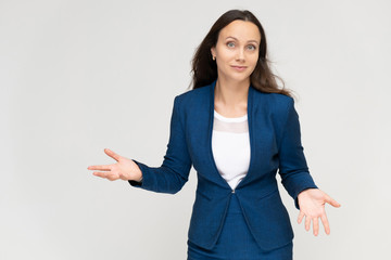 Portrait to the waist a young pretty brunette manager woman of 30 years in a business blue suit with beautiful dark hair. Standing on a white background, talking, showing hands, with emotions.