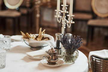 Waits for visitors. Picture of served table with bread sticks, plant in the water and silver colored kettle