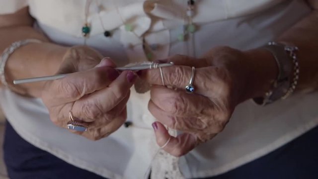 elderly crop woman crocheting while sitting relaxed at home 