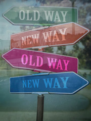 Signposts showing the new way old way, seen through the glass.