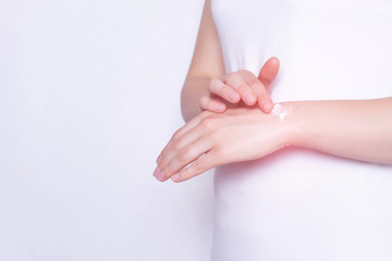 The girl rubs the healing ointment into the wrist joint against pain and inflammation in the joint, White background, copy space, stiffness