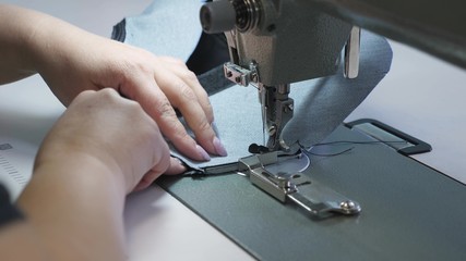 needle of the sewing machine in motion, close-up. needle of sewing machine quickly moves up and down. process of sewing leather goods. Tailor sews black leather in sewing workshop.