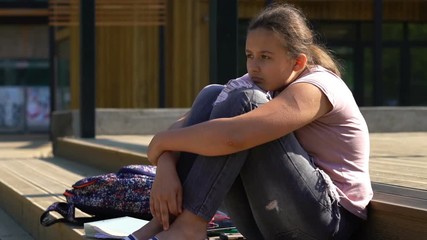 Sad, unhappy teenage girl sitting on stairs in the city