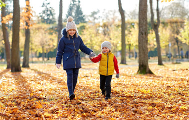 childhood, season and family concept - happy children walking at autumn park