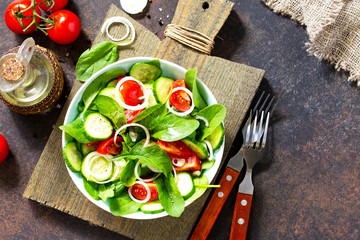 Vitamin snack. Salad with fresh vegetables and spinach on a dark stone or concrete table. Free space for your text.