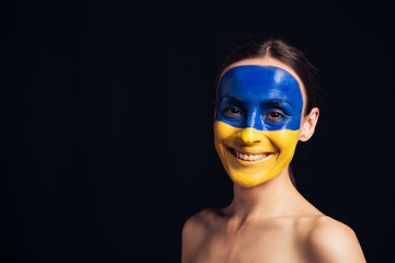 naked young woman with painted Ukrainian flag on skin smiling isolated on black
