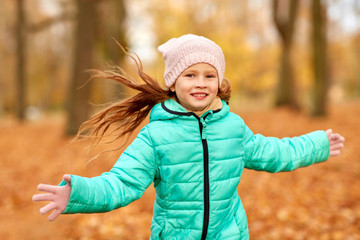 childhood, season and people concept - happy girl at autumn park