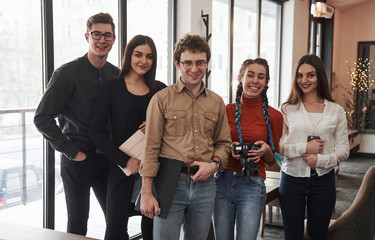 Backstage of photo session. Five young people standing indoors and looking straight into the camera