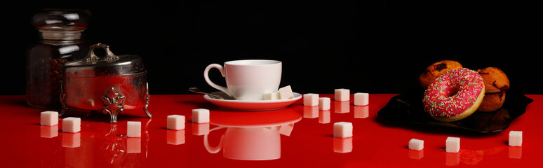Panorama with a Cup of coffee, a donut and sugar on a red glossy table