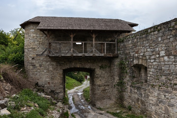 Fototapeta na wymiar Stone medieval gates with a stone wall next to. Complex of defensive buildings, XVI-XVIII centuries. Kamianets-Podilskyi, Ukraine.